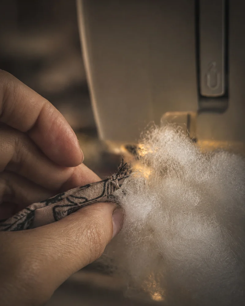 Hands stitching a doll body at the sewing machine